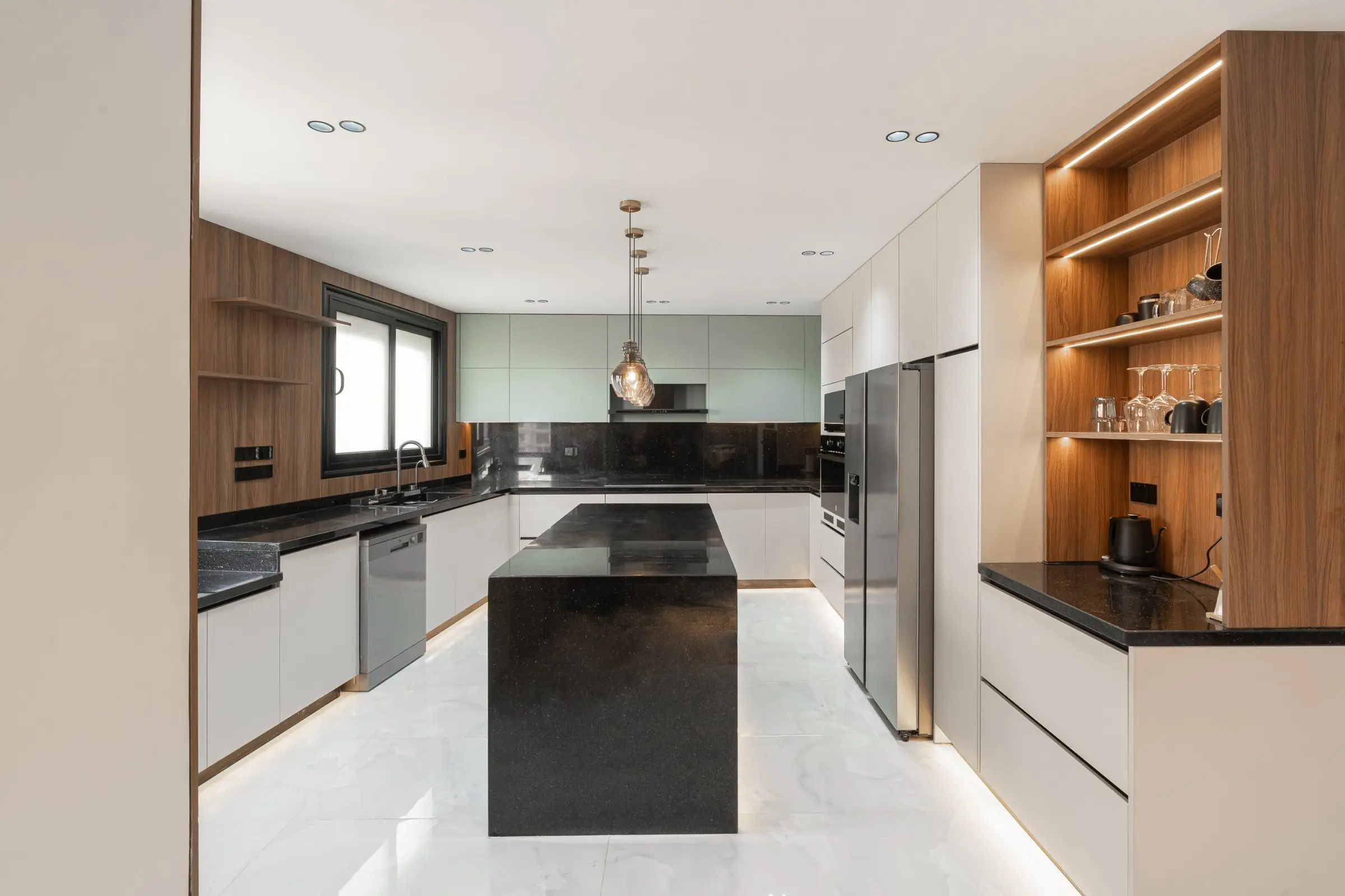 Stova U-shaped kitchen with a black stone island, walnut shelving and sage upper cabinets