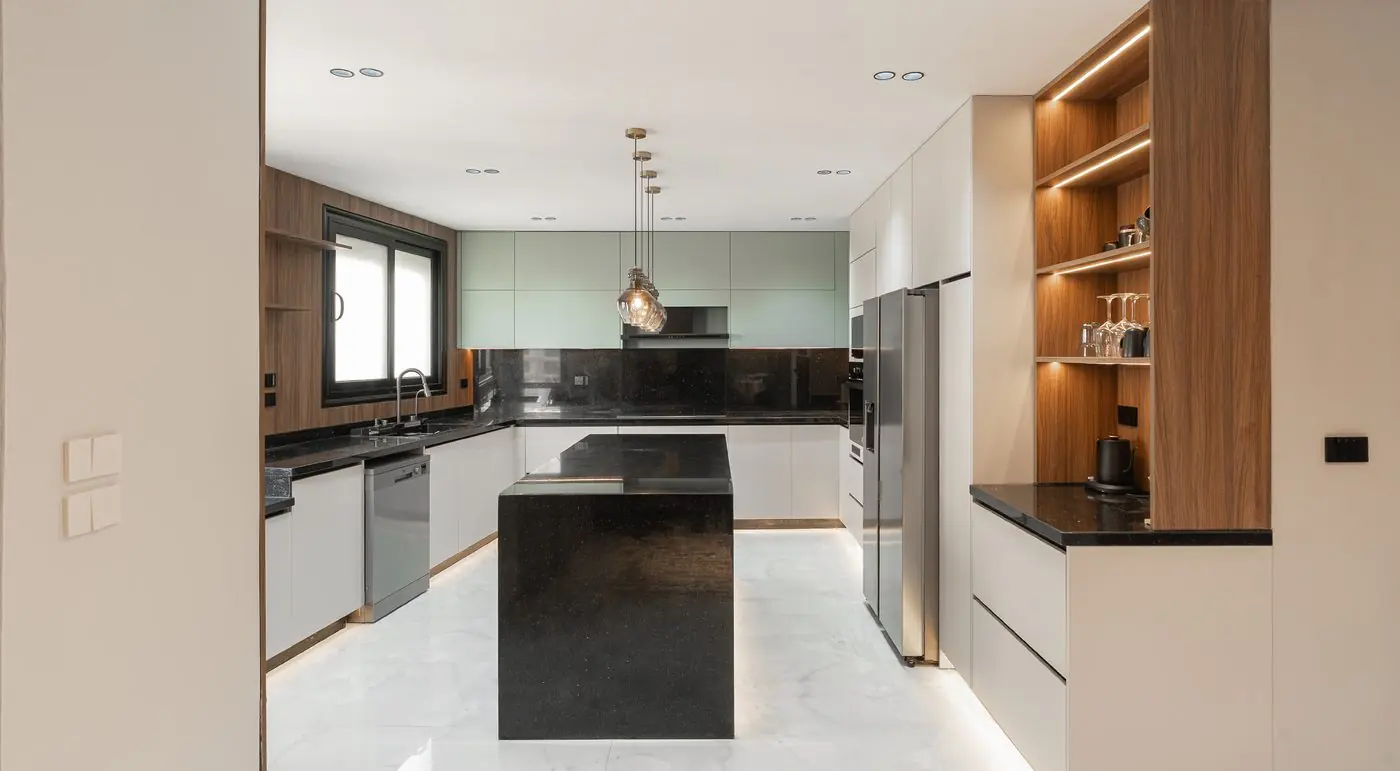 Kitchen with a black island and lit wooden shelving in Badya
